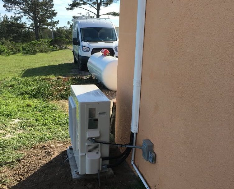 Work vehicle parked behind house with installed heat pump in the foreground